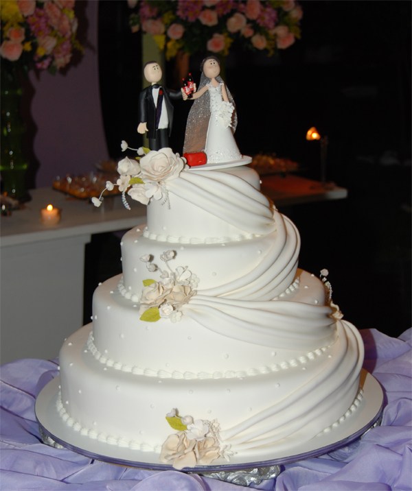 bolo medio de casamento enfeitado com flores e noivinhos